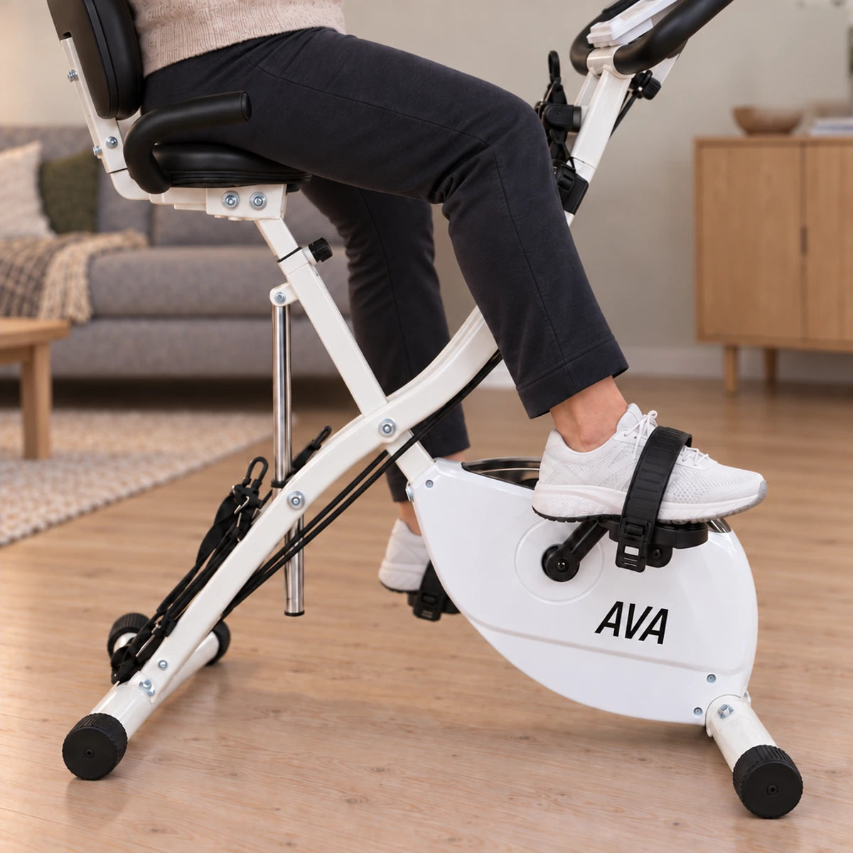 Nærbillede af ben og pedal fra siden på AVA foldbar motionscykel i stuen